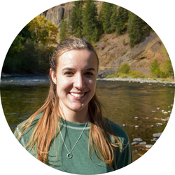 Tutor Emma standing in front of a river, with mountains and trees in the background.